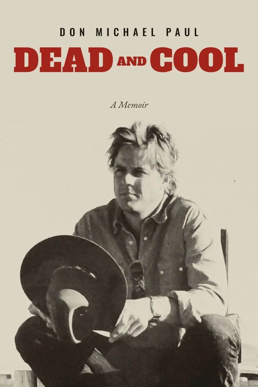 Dead and Cool, a memoir by Don Michael Paul: cover photo of Don on the set of Harley Davidson and the Marlboro Man, sitting on a fence rail with a cowboy hat